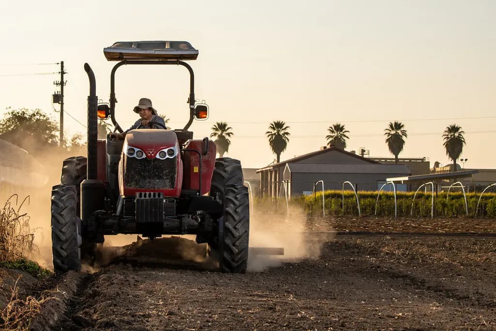 Tracteur travaillant un champ au coucher du soleil