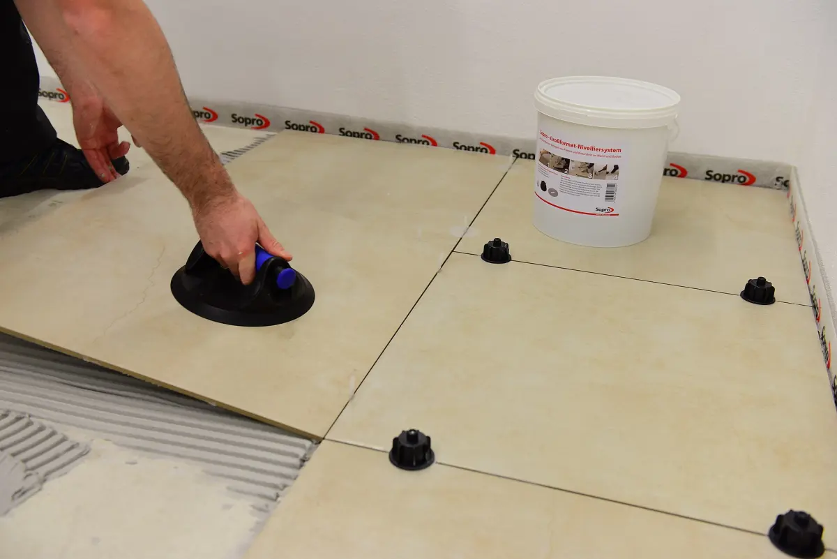 Pose de grands carreaux sur colle avec ventouse et croisillons de nivellement