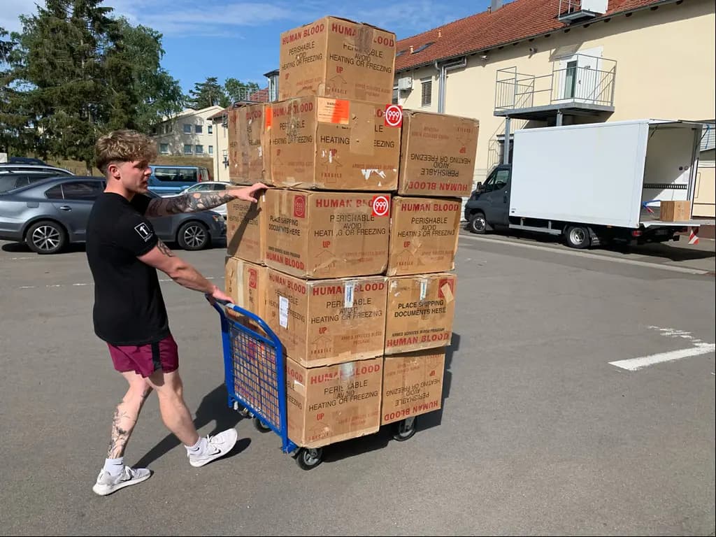 Manutentionnaire poussant un diable chargé de cartons